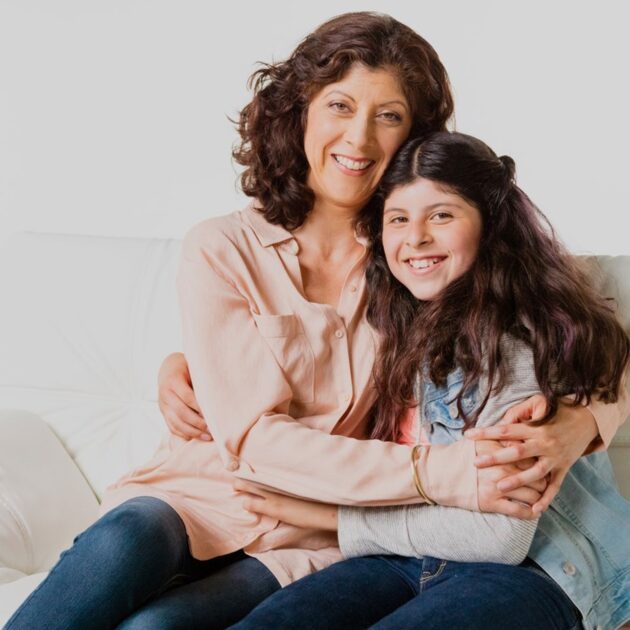 A woman and young girl hugging on a couch
