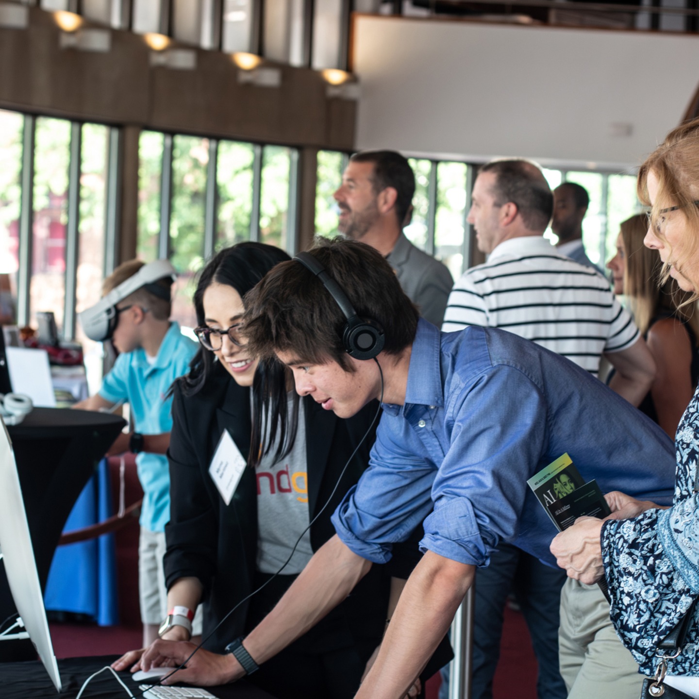 A crowd of people at a conference crowd around a laptop