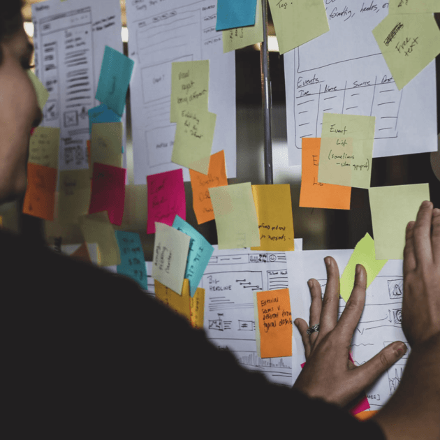 Image of someone placing sticky notes on wireframes in a workshop