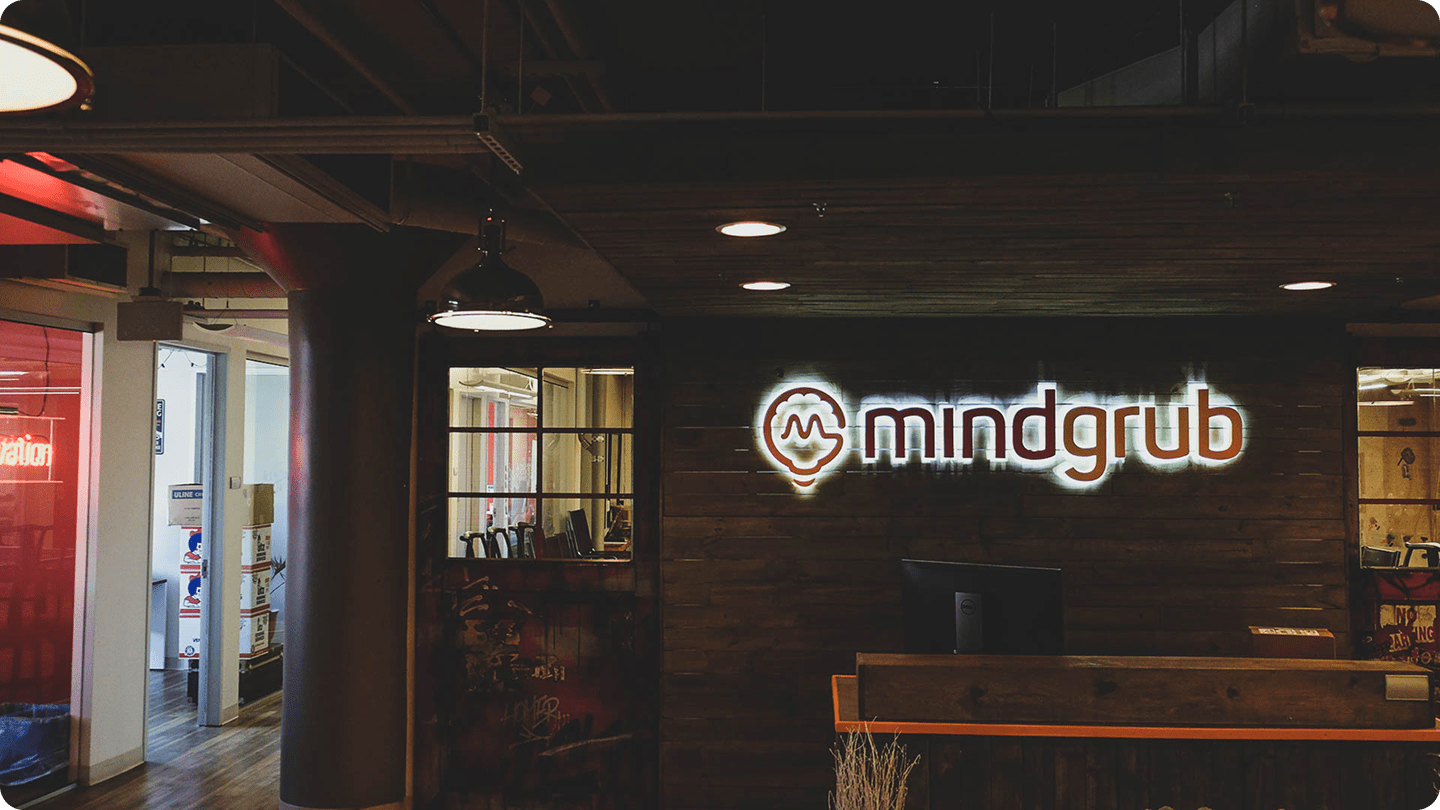 The Mindgrub office front lobby. A neon sign of the Mindgrub logo hung above the front desk.