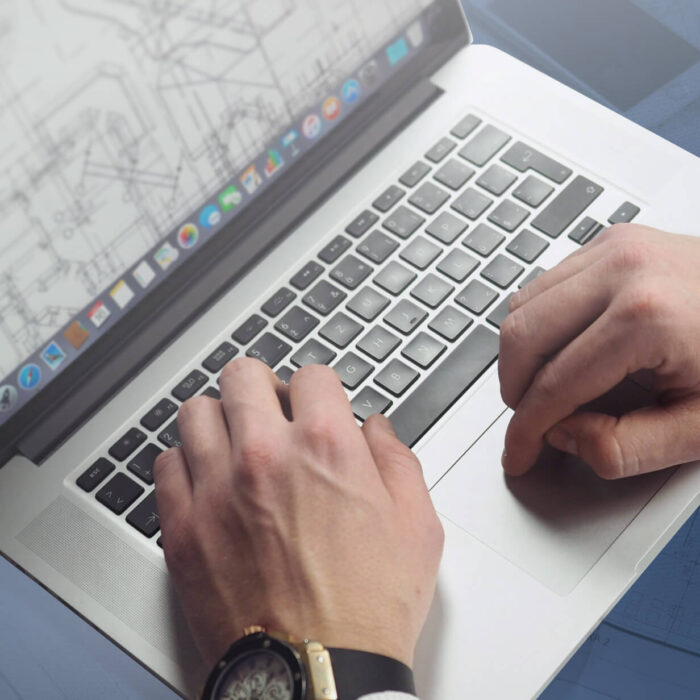 Person working with architectural floor plans on a laptop.
